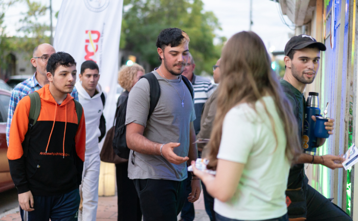 Una adolescentes reparte folletería a sus pares en la calle, frente a la escuela técnica de Libertad