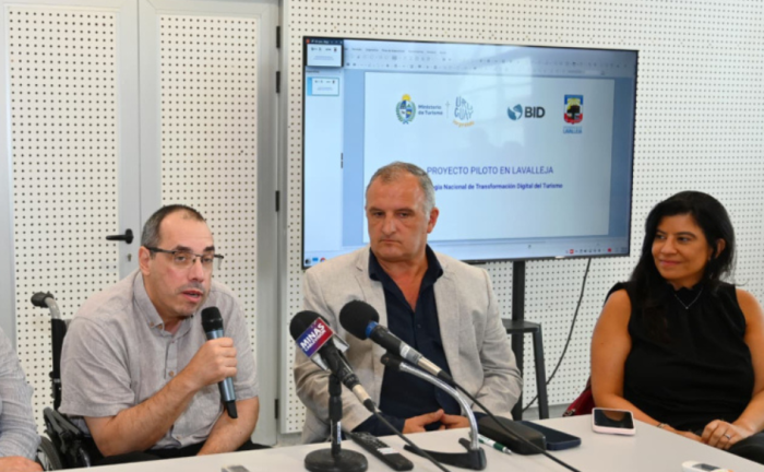 Ministro de Turismo, Pablo Menoni, habla con micrófono en mano. A su lado, el intendente de Lavalleja, Daniel Ximénez