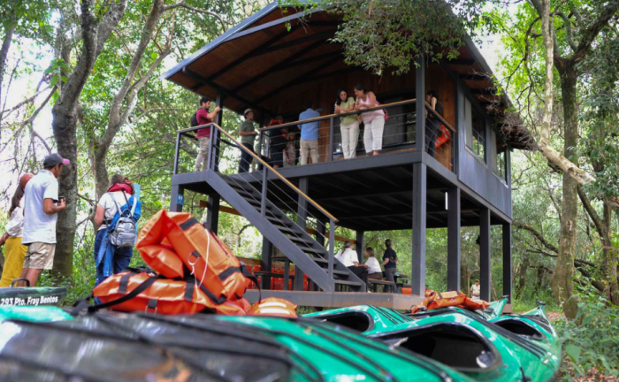 Turismo procura ampliar cantidad de destinos inteligentes en todo el país Turistas conversan y toman fotografías en una cabaña. Delante, dos botes