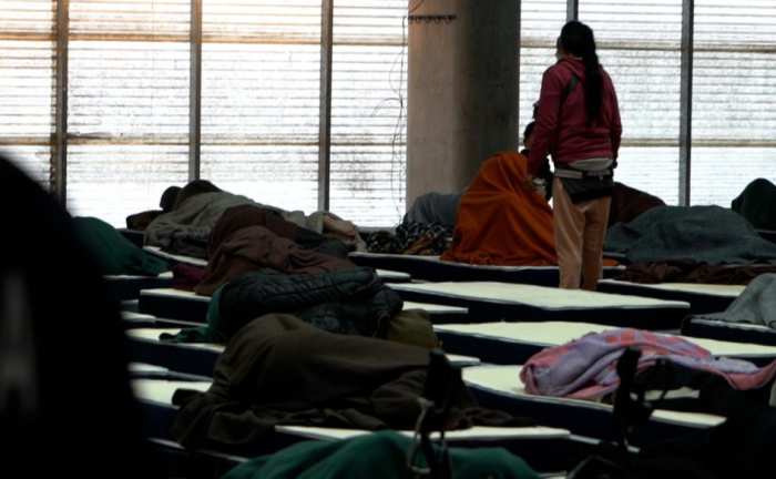 Persona de pie entre las camas dispuestas en fila en un centro de evacuación del Sinae