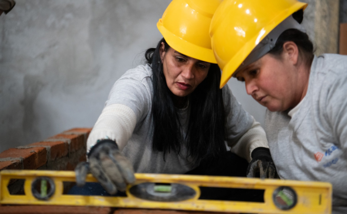 Más Barrio impulsa mejoras habitacionales en Cerro Norte Dos mujeres, con cascos y guantes, trabajan en la reparación de una casa