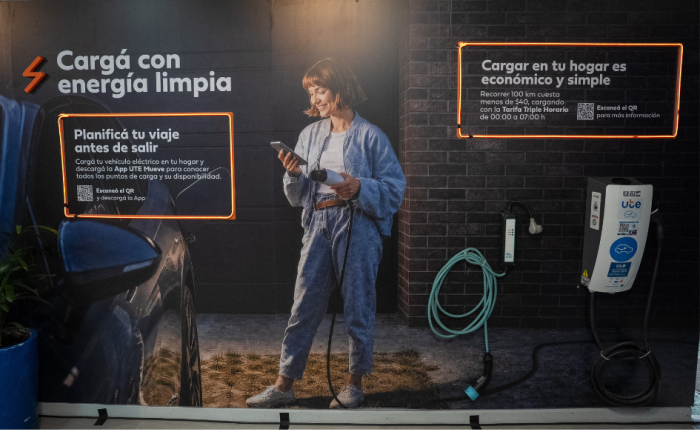 Expo Prado 2026: UTE inauguró stand y reafirmó su apoyo al sector productivo Imagen interior del stand de UTE en la Expo Prado 2026. Una mujer joven sostiene un cargador de autos eléctricos. Se lee "Cargá con energía limpia" y "Cargar en tu hogar es económico y simple"