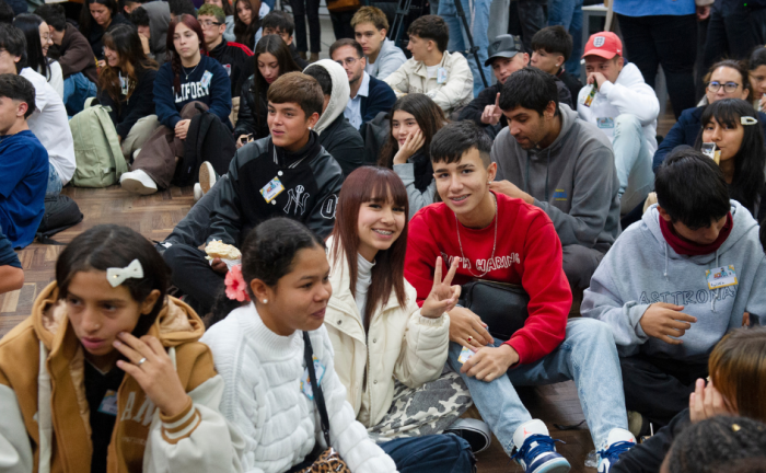 Decenas de adolescentes están sentados en el piso, en la sede del INJU. Dos de ellos, observan a la cámara sonrientes y con los dedos índice y mayor levantados, formando una "v"