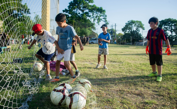 Cuatro niños de unos 10 años juegan al fútbol en una cancha