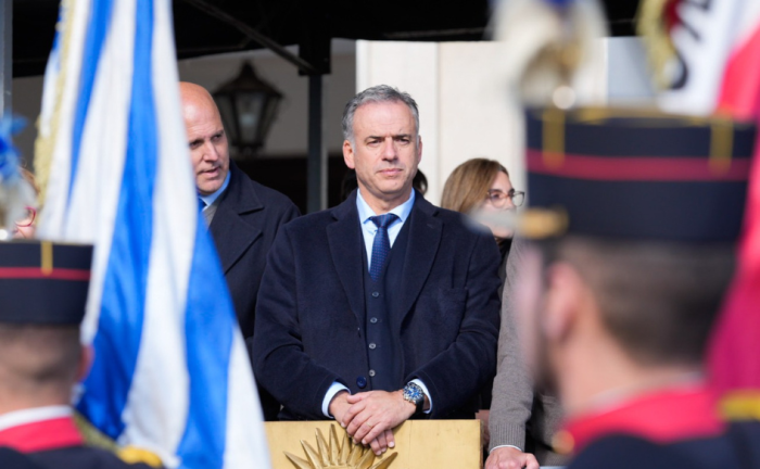 Presidente Orsi ratificó rumbo económico del Gobierno Presidente Yamandú Orsi, de pie, con una mano apoyada arriba de la otra. Delante de él, el pabellón nacional