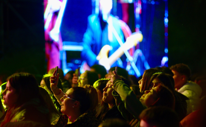 Carnaval: Se invita a disfrutar con alegría y responsabilidad Jóvenes disfrutan de espectáculo musical. De fondo, una pantalla gigante muestra al artista