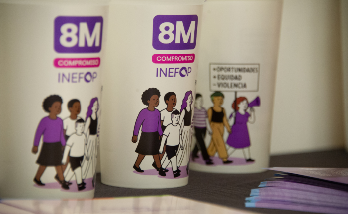 Vasos sobre una mesa con un dibujo de mujeres caminando. En ellos, la leyenda "8M Compromiso Inefop"