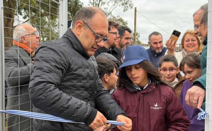 Familias de Coronilla de Caraguatá, en Rivera, acceden al servicio de agua potable Vicepresidente de OSE, Guillermo Caraballo, corta una cinta de inauguración junto a una niña en Coronilla de Caraguatá, Rivera. Detrás de ellos, varias personas observan alegres la situación