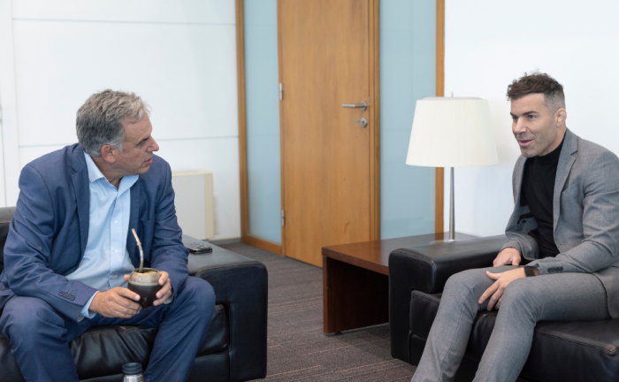 Presidente Orsi sentado en un sillón, con el mate en la mano. En otro sillón está sentado Gastón Reyno