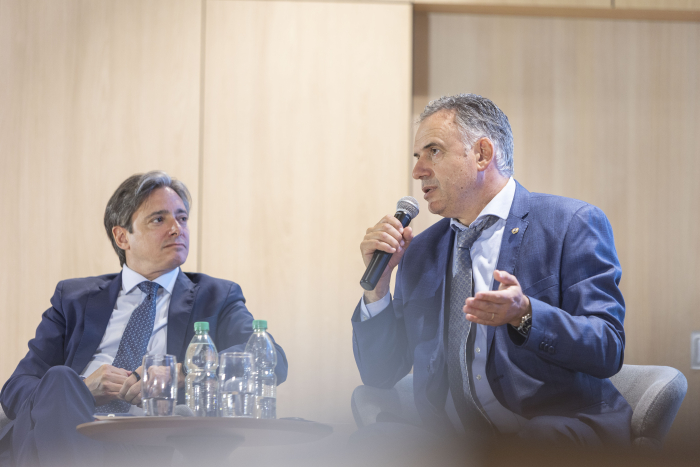 Presidente Yamandú Orsi, sentado en un sillón, habla con un micrófono en la mano. A su lado, Christian Asinelli, vicepresidente de Programación Estratégica de CAF, lo observa atentamente 