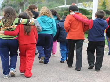 Niños y niñas caminando abrazados