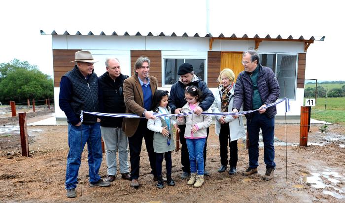 Autoridades del Ministerio de Vivienda y de Mevir junto a familia beneficiada corta la cinta de inauguración 