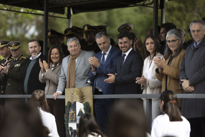 El presidente Yamandú Orsi, parado, aplaude a un grupo de personas que desfilan en Sarandí Grande. A su lado, el intendente de Florida, Caros Enciso y el alcalde de Sarandí Grande, Maximiliano Ripoll