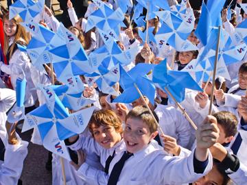 Niños y niñas con molinetes con colores celestes y blancos