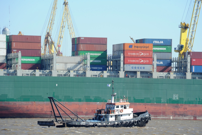 Exportaciones de bienes alcanzaron su mayor nivel en una década Buque portacontenedores arriba a puerto de Montevideo. Delante de él, un barco remolcador.