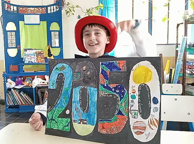 Estudiante de escuela rural sostiene una cartulina con la leyenda "2050"