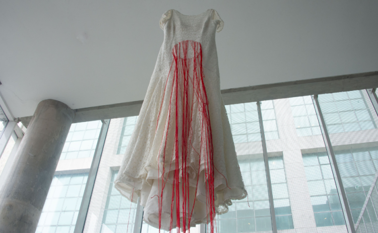 Vestido blanco con hilos rojos cuelga desde el techo del hall del anexo a la Torre Ejecutiva