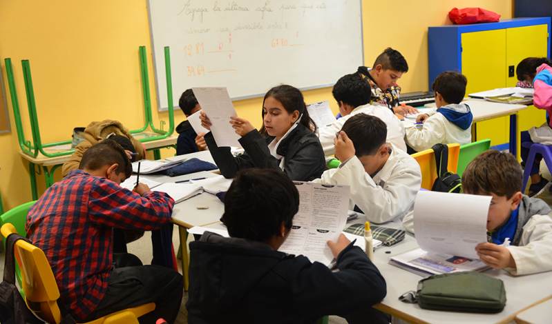 Escolares en un aula, trabajan sobre sus mesas