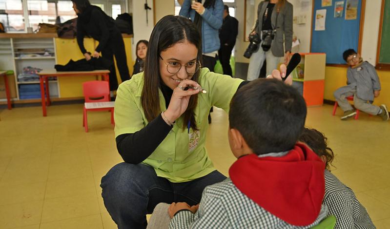 Oftalmóloga le hace una pesquisa a un niño en un salón de clases