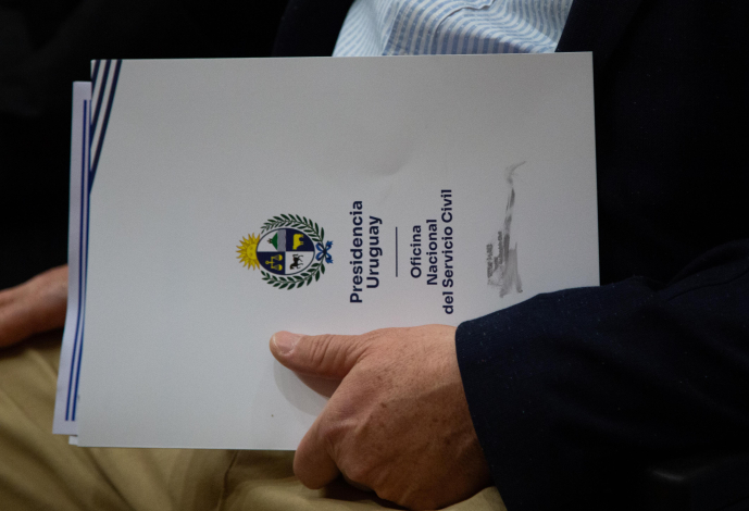Persona sentada con una carpeta de la ONSC en su mano
