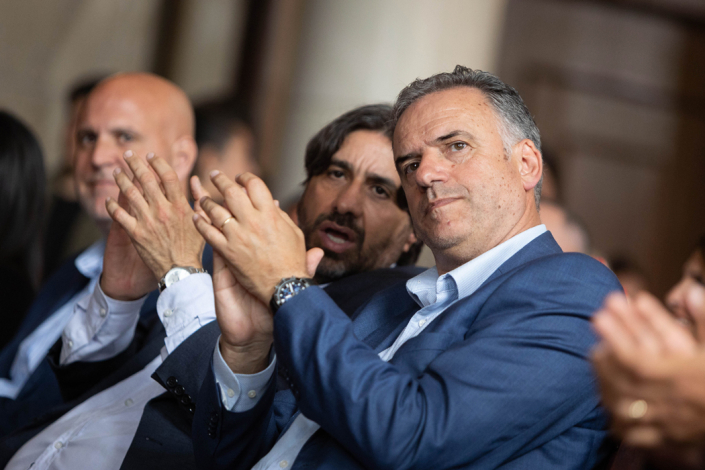 Presidente Yamandú Orsi en primer plano, sentado en el público, dialoga con Marcelo Metediera de Unasev