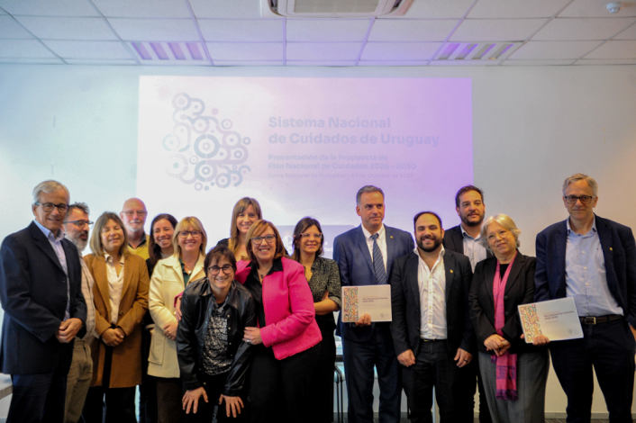 El presidente de la República, Yamandú Orsi, sostiene el documento impreso del plan nacional de Cuidados. Junto a él, el