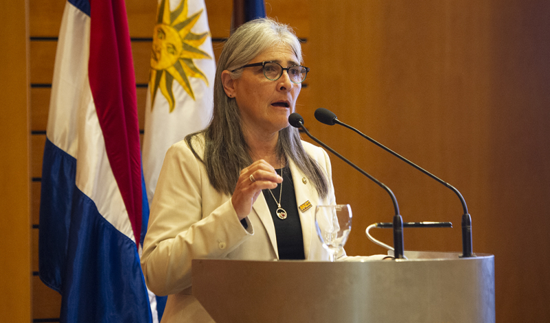 Ministra de Transporte y Obras Públicas, Lucía Etcheverry, brinda discurso detrás de un estrado. Detrás luce el pabellló