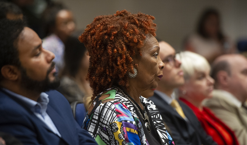Mujer afrodescendiente, sentada, observa atentamente la presentación de las autoridades de Riafro