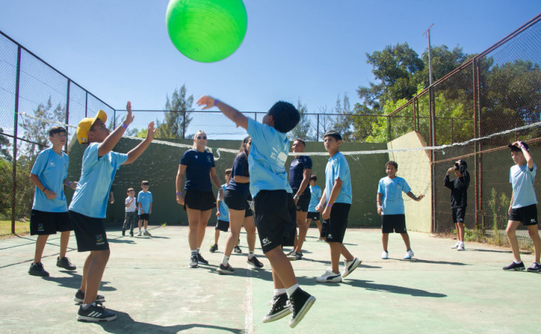 Niños juegan al voleyball con una pelota de grandes dimensiones