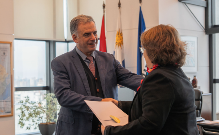 Presidente Yamandú Orsi saluda a la embajadora de Cuba, Lissett Pérez, con un apretón de manos. Ella sostienen sus carta