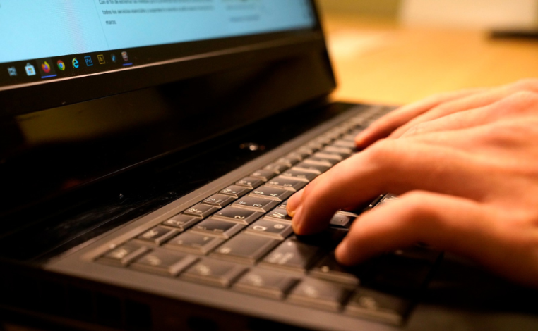 La mano de una persona está apoyada en el plano de una notebook
