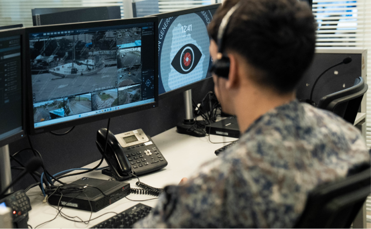 Funcionario del Centro de Comando Unificado observa un monitor, con auriculares puestos