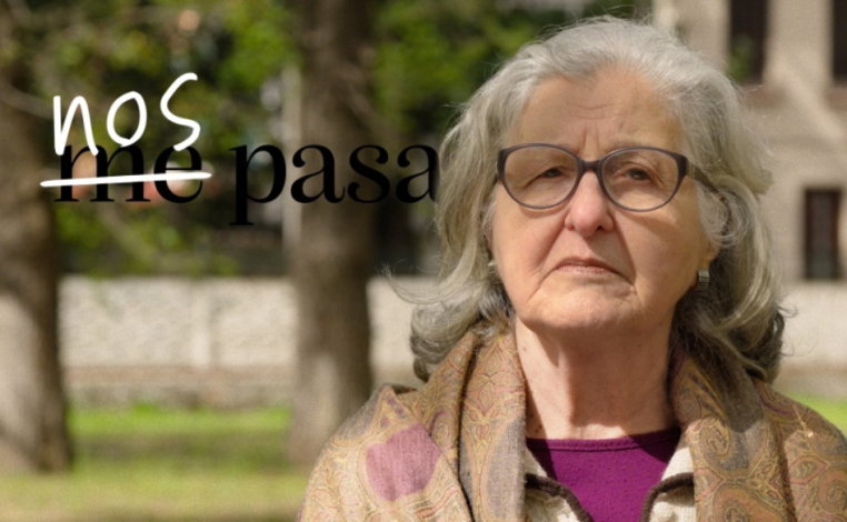 Portada de la campaña Nos Pasa. Una señora mayor mira la cámara, con un semblante triste, en un espacio público. A su la