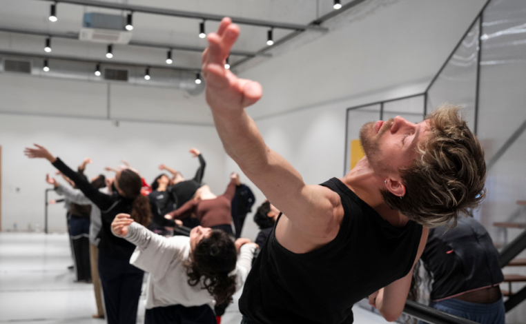 Estudiantes de ballet de la Escuela de Formación Artística del Sodre, dispuestos en fila, ensayan una puesta en escena,