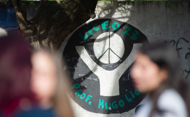 Adolescentes en el patio del liceo n°23. De fondo, el logo del liceo pintado en un muro