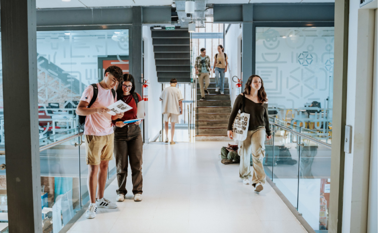 Estudiantes de UTEC observan un follero. A su lado, otra estudiante camina por un pasillo