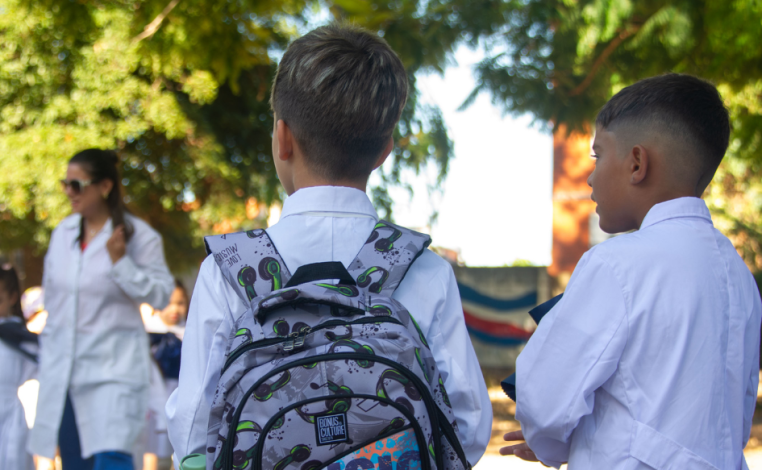 Dos escolares, de espaldas, en el patio de una escuela