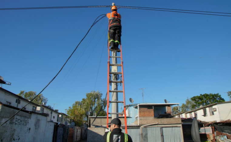 Funcionario de la Intendencia de Montevideo, subido a una escalera, manipula el cableado del alumbrado público en Cerro 
