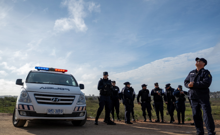 Una decena de policías de pie, al lado de un móvil policial, en un barrio del departamento de Rivera, cerca de la fronte