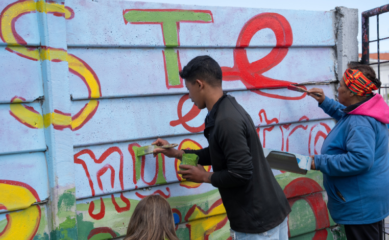 Un adolescente y una mujer pintan el muro de la plaza de deportes n°10 de Cerro Norte, durante jornada comunitaria del p