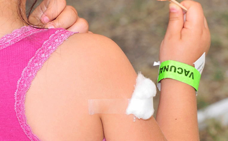 Brazo de una niña con un algodón, tras vacunarse