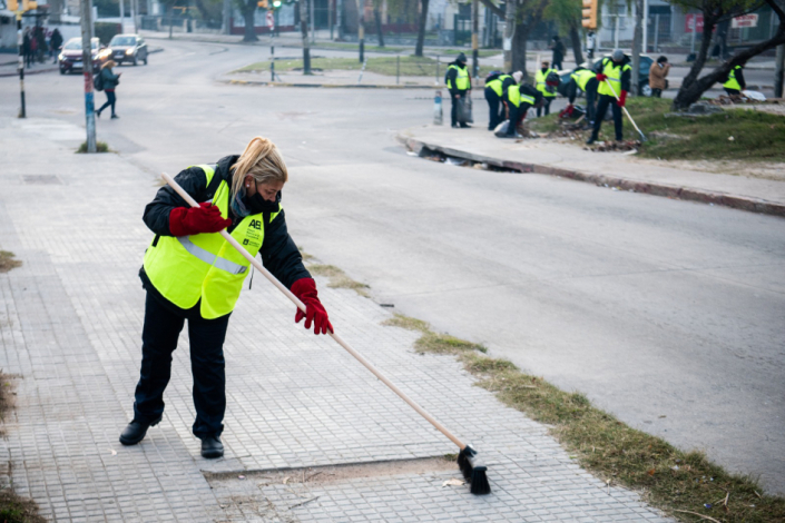 Mujer barriendo la vereda