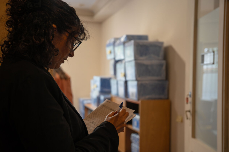 Mariana Risso participa del registro y control de los archivos trasladados a la INDDHH. Mariana Risso completa una planilla frente a cajas de archivo embaladas.