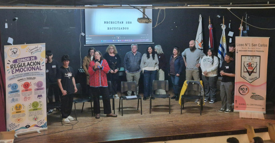 Participantes de una jornada sobre salud mental posan en el escenario del Liceo N.º 1 de San Carlos.