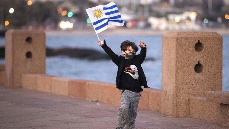 Un niño flamea una bandera de Uruguay. 