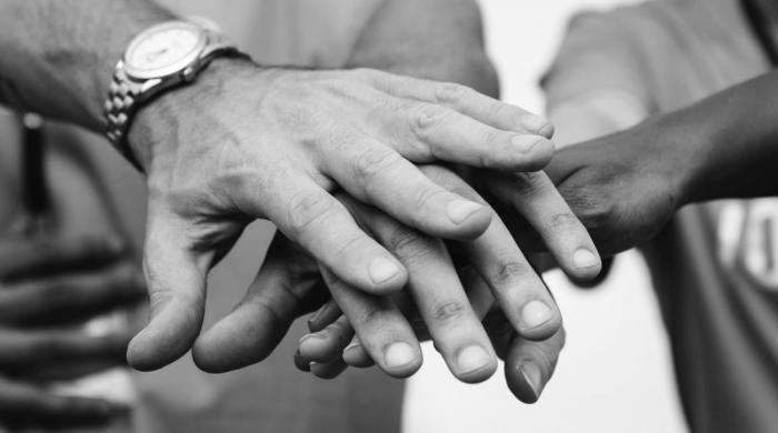 Participación Manos una arriba de la otra en blanco y negro