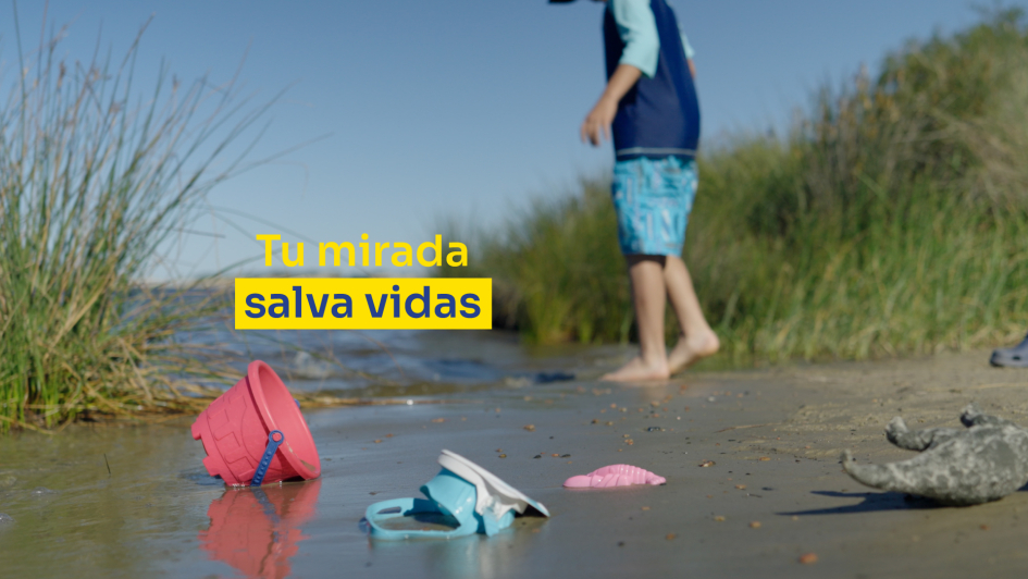 Un niño en la orilla de un río junto a sus juguetes.