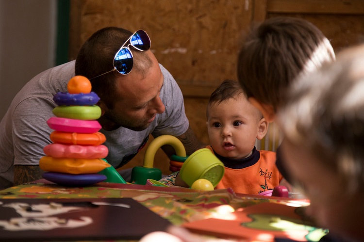 Justin de 7 meses sentado en una mesa de juegos de su centro educativo junto a su madre y su padre