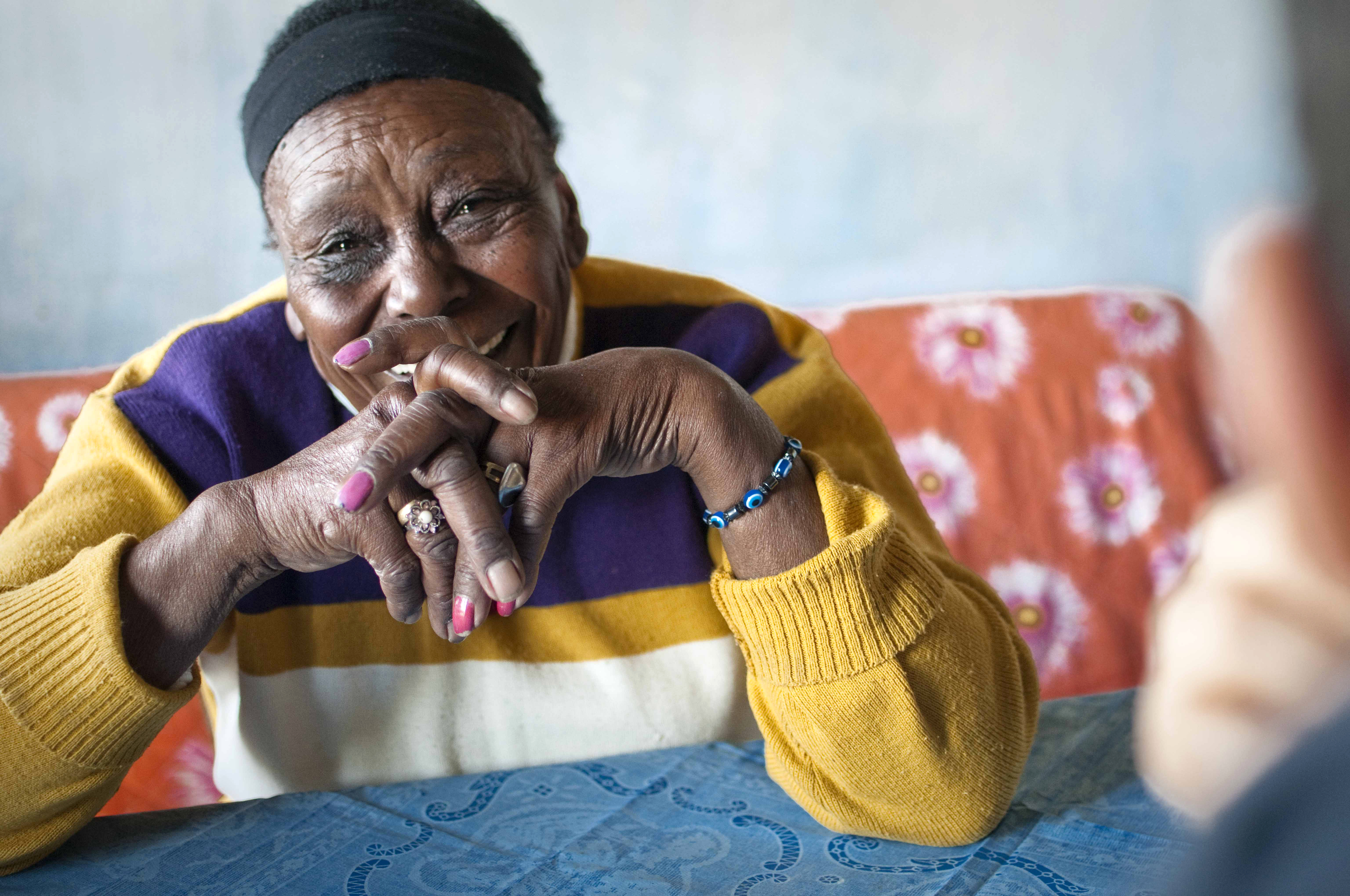 Mujer mayor sentada en una mesa entrecruzando los dedos