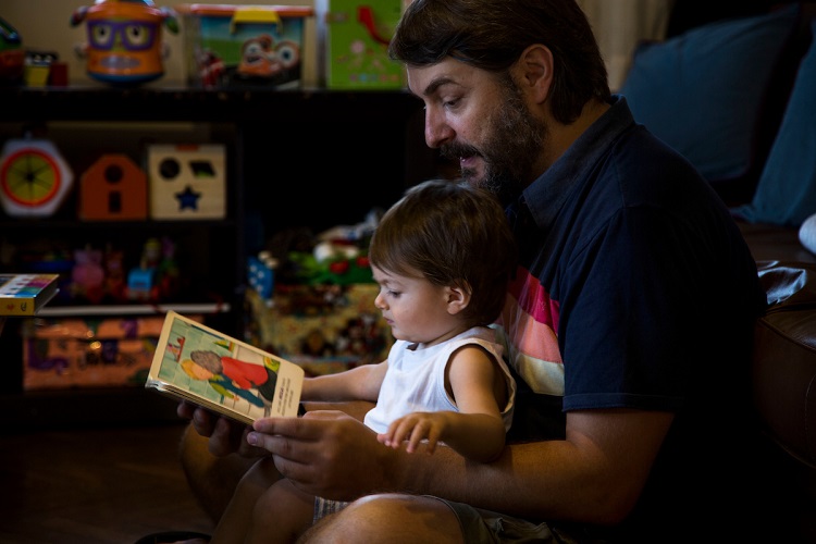 Padre lee cuidando a su hijo pequeño, leyendo un cuento